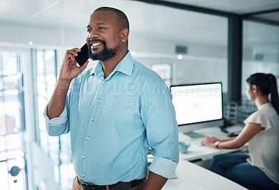 Buy stock photo Cropped shot of a handsome young businessman standing and using his cellphone while a colleague works behind him