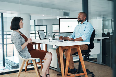 Buy stock photo Cropped shot of two young businesspeople sitting in the office together and having a discussion