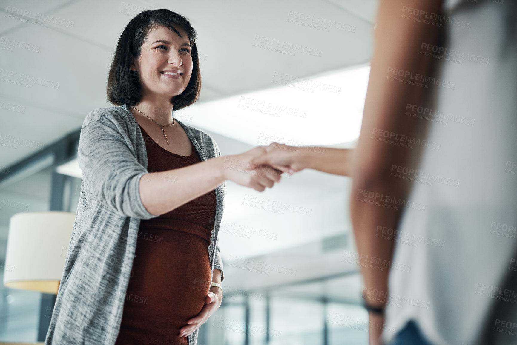 Buy stock photo Cropped shot of an attractive pregnant businesswoman standing and shaking hands with a colleague in the office