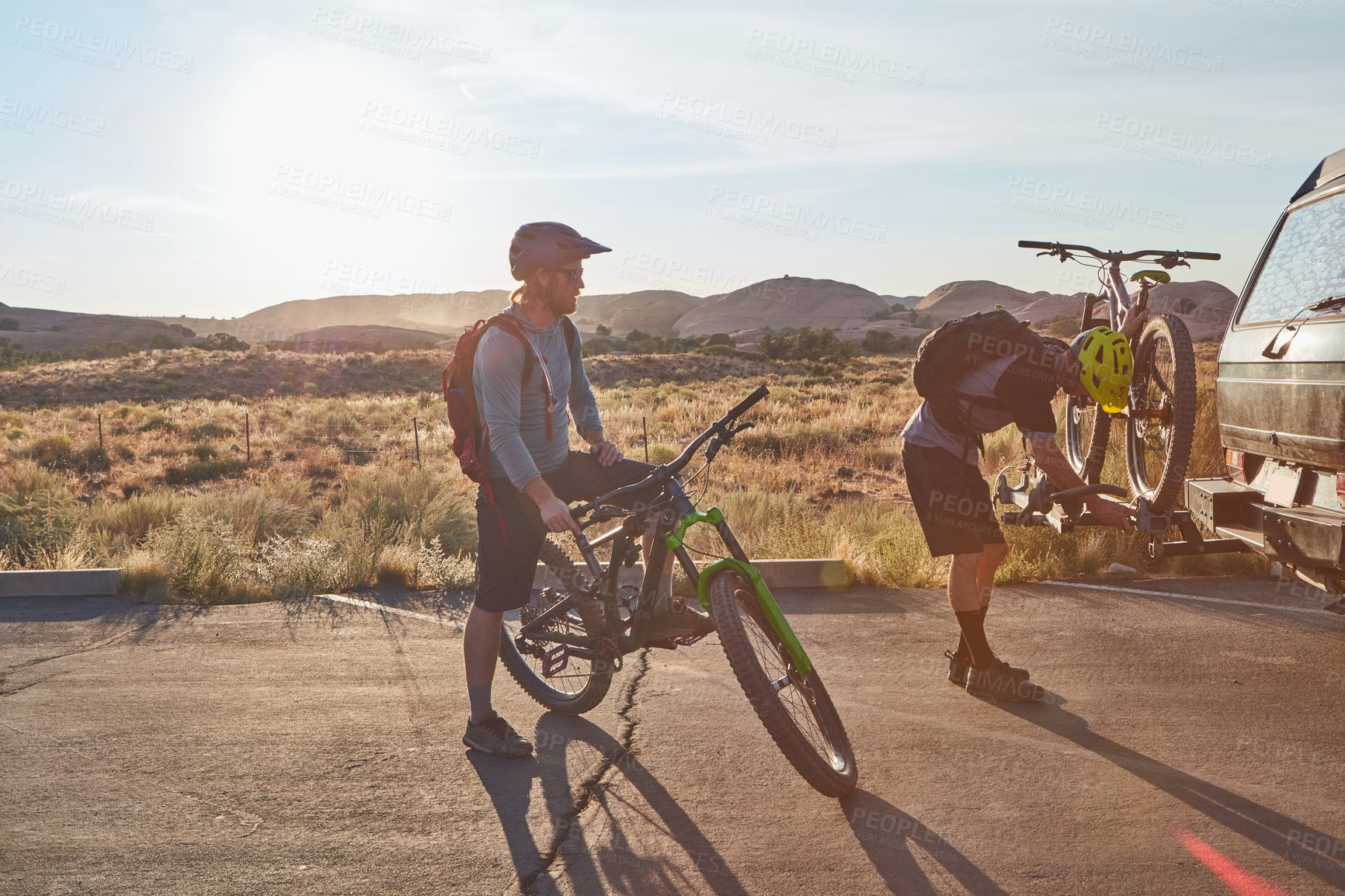 Buy stock photo Full length shot of two young male athletes mountain biking in the wilderness