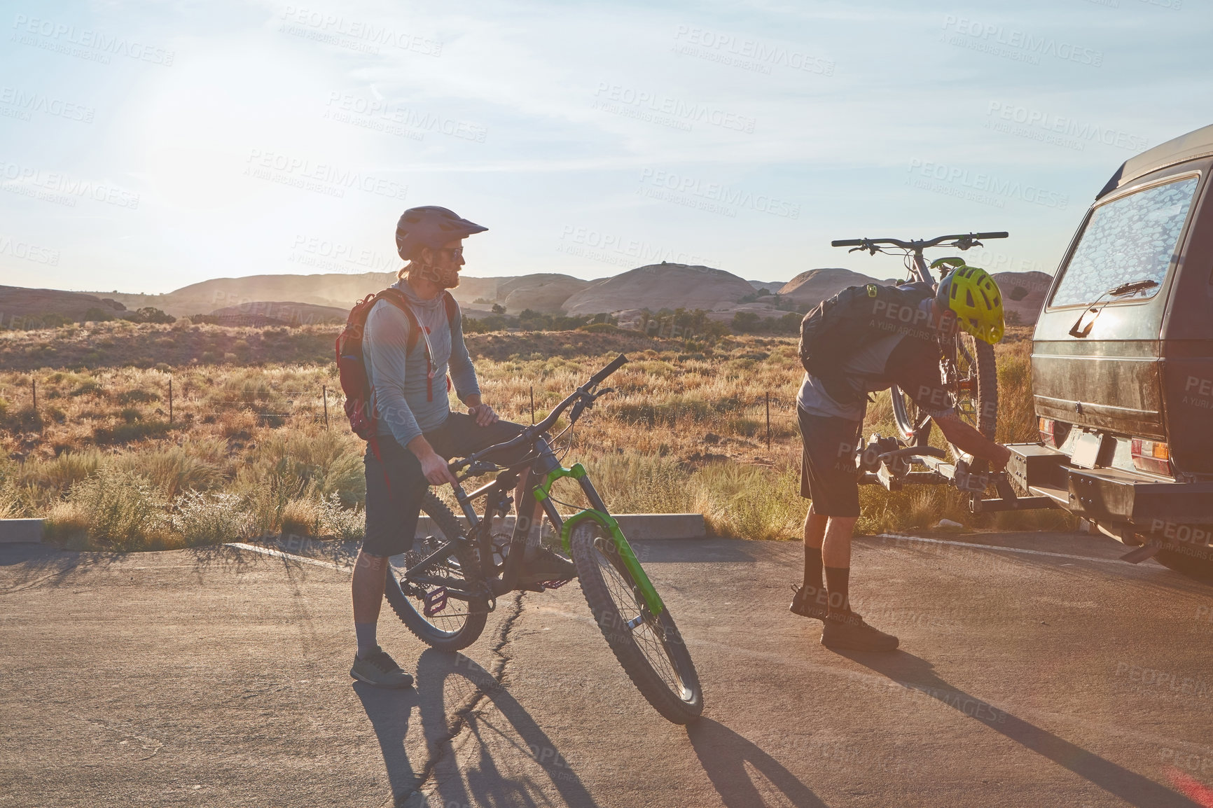 Buy stock photo Full length shot of two young male athletes mountain biking in the wilderness