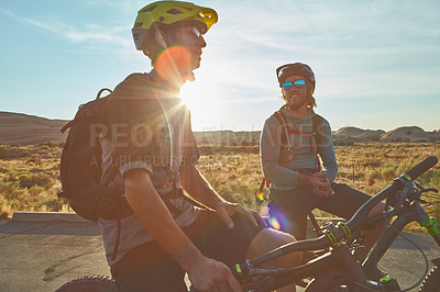 Buy stock photo Cropped shot of two young male athletes mountain biking in the wilderness