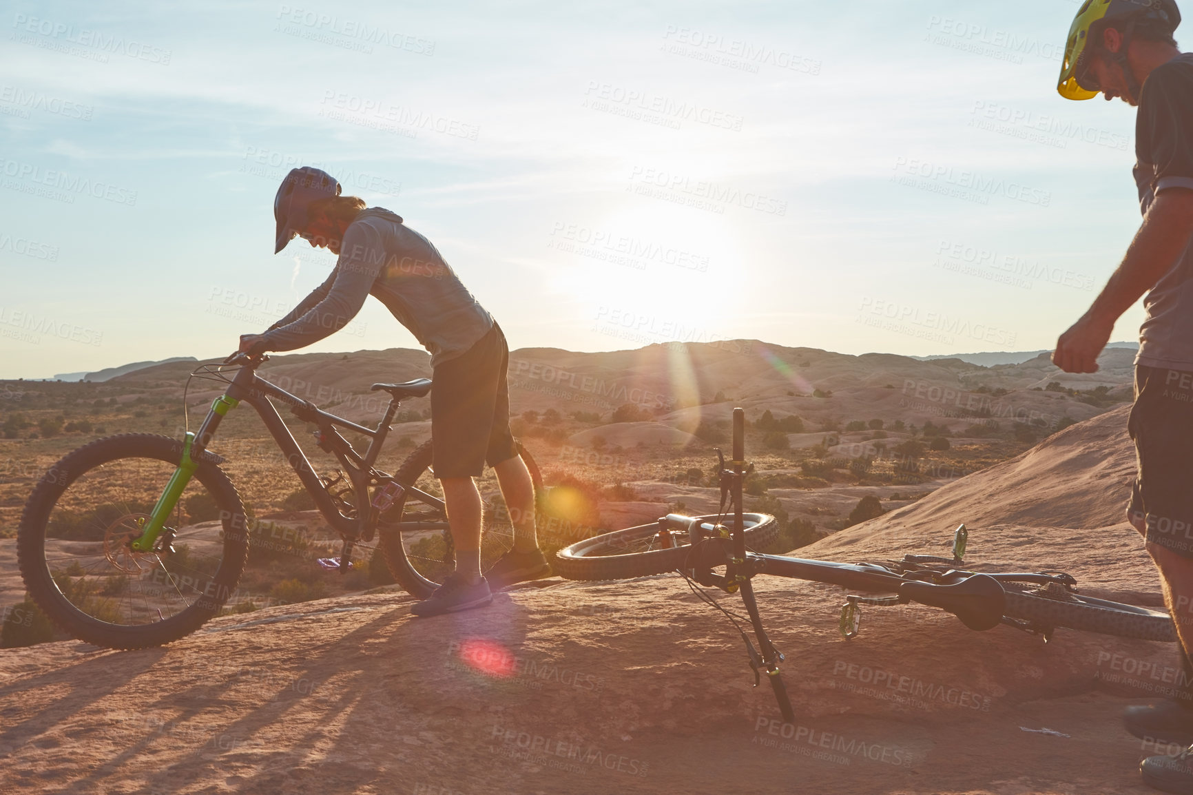 Buy stock photo Full length shot of two young male athletes mountain biking in the wilderness