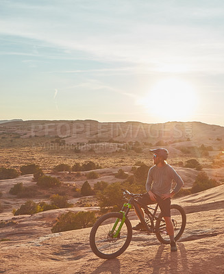 Buy stock photo Full length shot of two young male athletes mountain biking in the wilderness