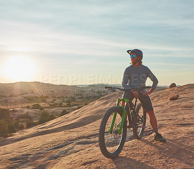 Buy stock photo Full length shot of a young male athlete mountain biking in the wilderness