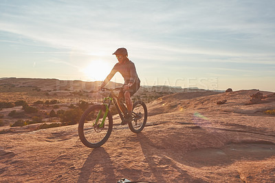 Buy stock photo Full length shot of a young male athlete mountain biking in the wilderness