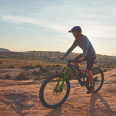 Buy stock photo Full length shot of a young male athlete mountain biking in the wilderness