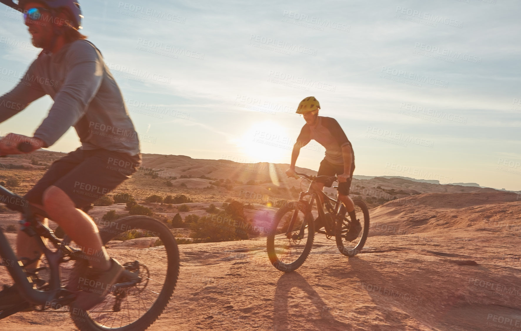 Buy stock photo Full length shot of two young male athletes mountain biking in the wilderness