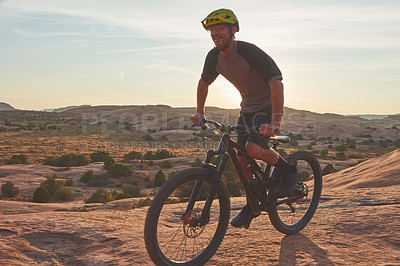 Buy stock photo Full length shot of a young male athlete mountain biking in the wilderness