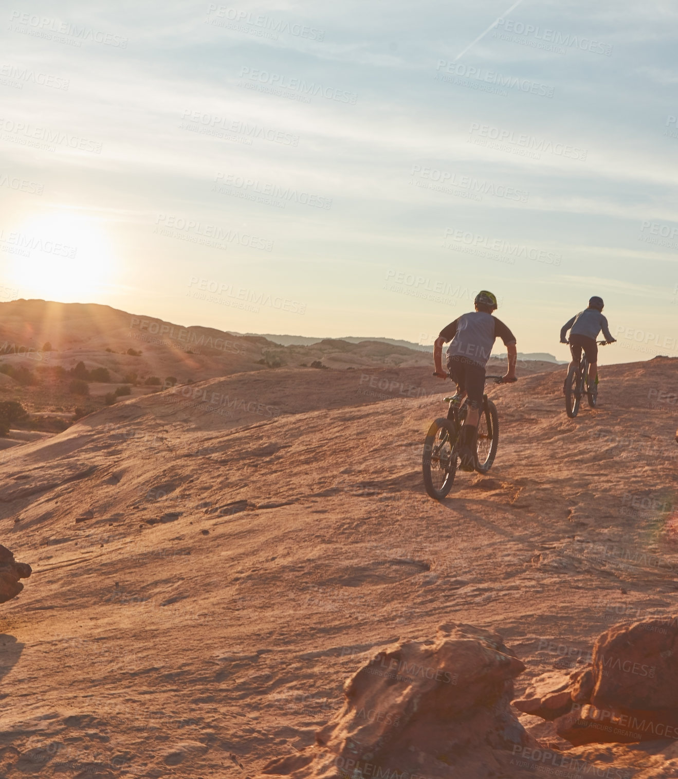 Buy stock photo Full length shot of two young male athletes mountain biking in the wilderness