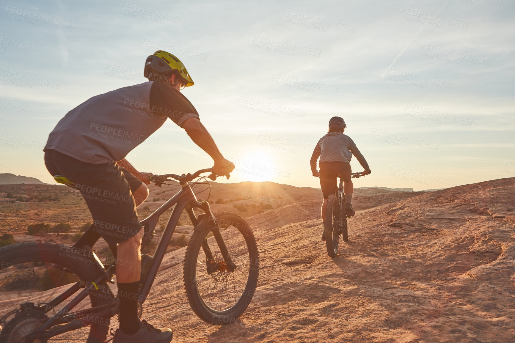 Buy stock photo Full length shot of two young male athletes mountain biking in the wilderness