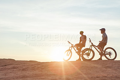 Buy stock photo Full length shot of two young male athletes mountain biking in the wilderness