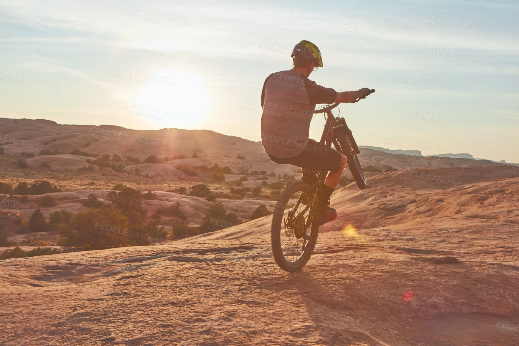 Buy stock photo Full length shot of a young male athlete popping a wheelie while mountain biking in the wilderness