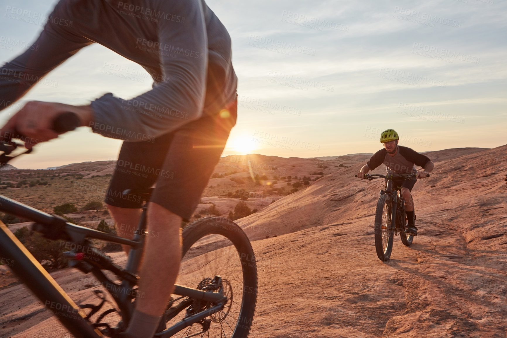 Buy stock photo Full length shot of two young male athletes mountain biking in the wilderness