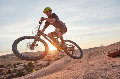 Buy stock photo Full length shot of a young male athlete mountain biking in the wilderness