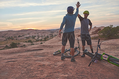 Buy stock photo Shot of two men giving each other a high five while out mountain biking