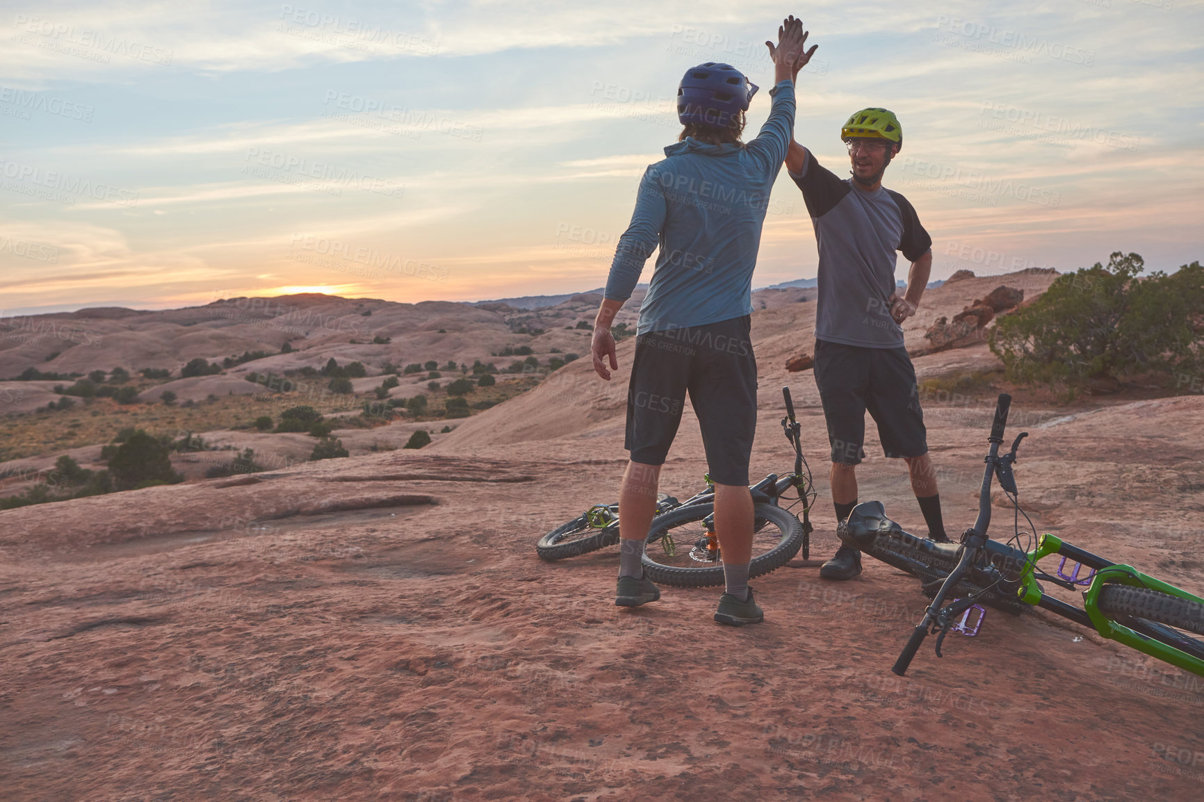 Buy stock photo Shot of two men giving each other a high five while out mountain biking