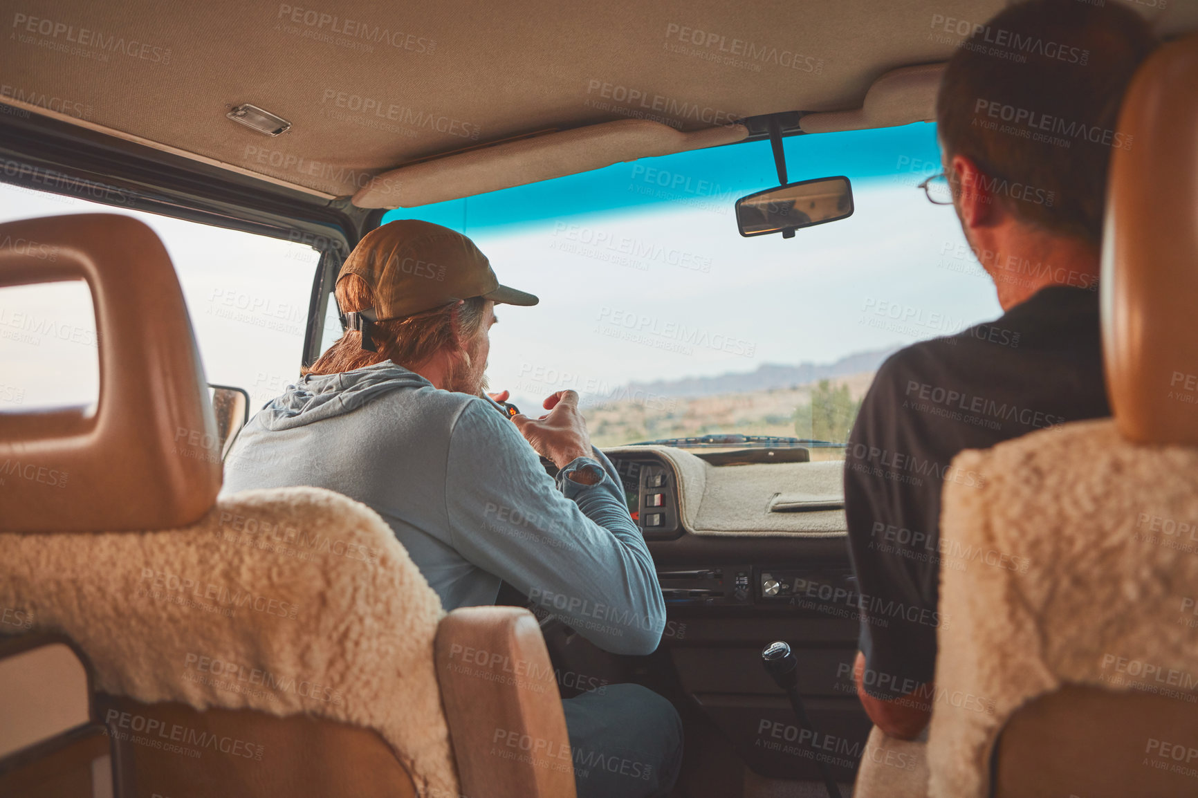 Buy stock photo Shot of two men smoking together while out on a road trip