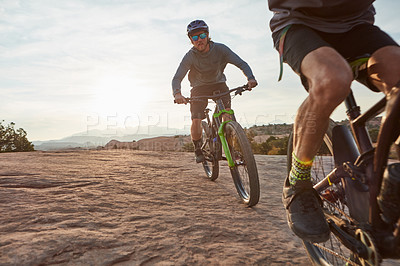 Buy stock photo Shot of two men out mountain biking together during the day