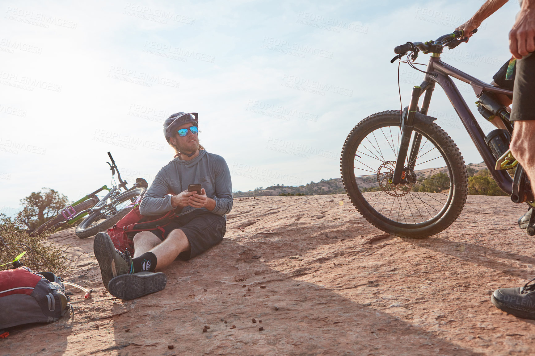 Buy stock photo Cropped shot of two athletic men taking a break while mountain biking through the wilderness