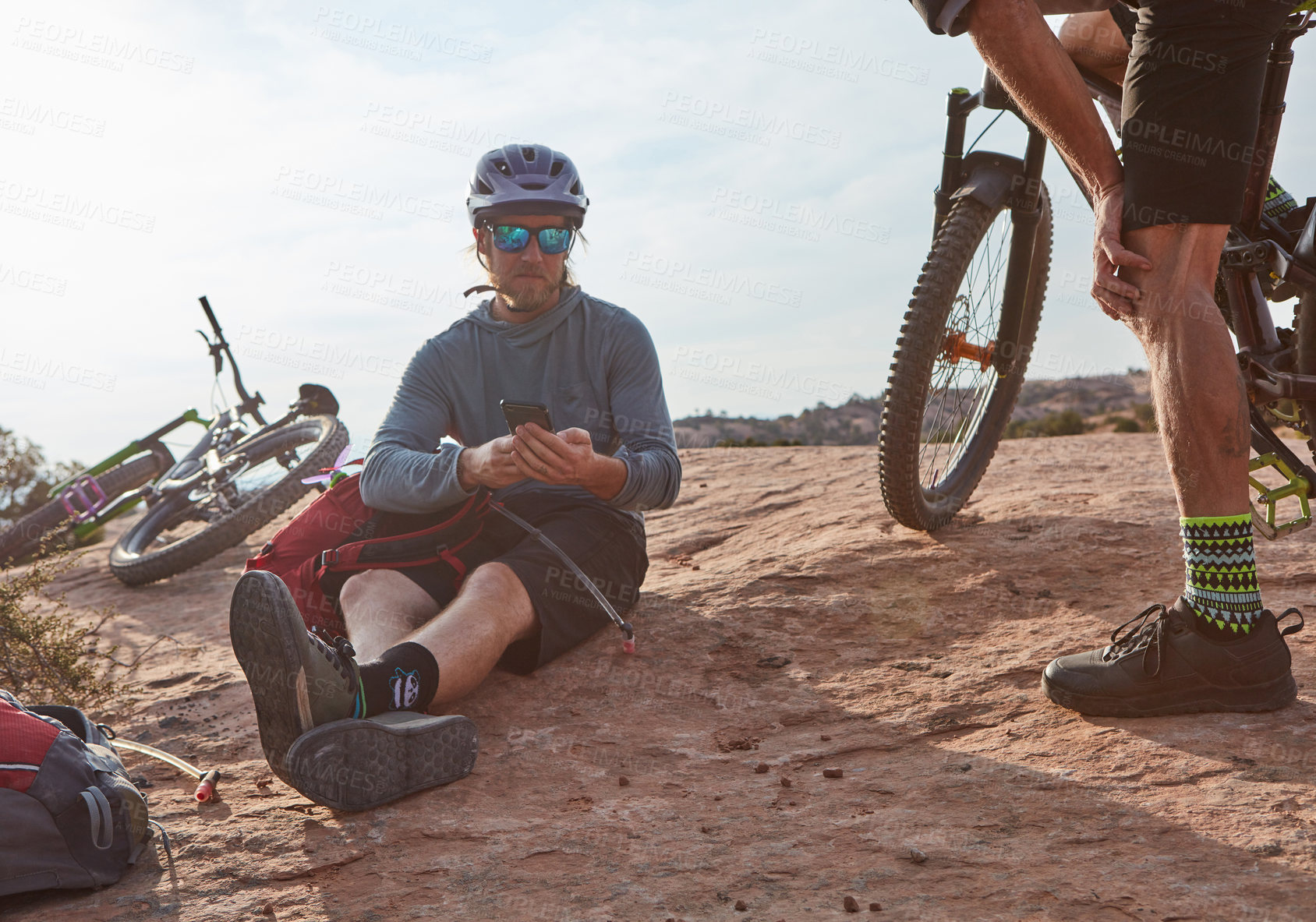 Buy stock photo Cropped shot of two athletic men taking a break while mountain biking through the wilderness