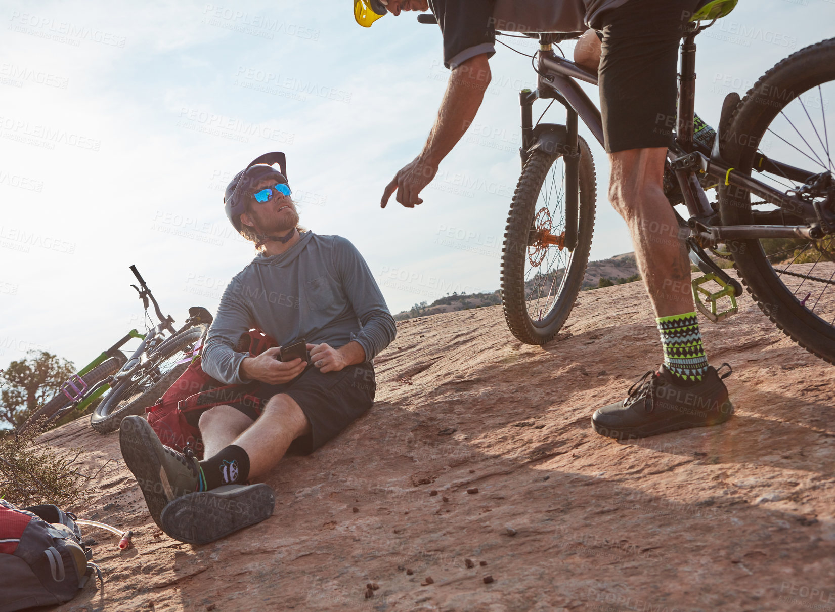 Buy stock photo Cropped shot of two athletic men taking a break while mountain biking through the wilderness