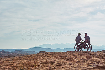 Buy stock photo Full length shot of two athletic men taking a break to admire the view while mountain biking through the wilderness