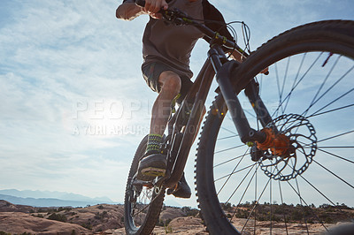 Buy stock photo Cropped shot of an unrecognizable athletic man mountain biking through the wilderness