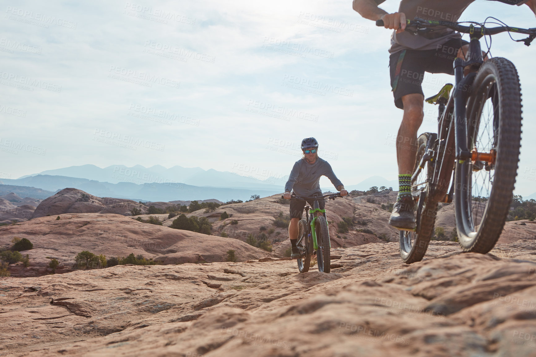 Buy stock photo Cropped shot of two athletic men mountain biking through the wilderness