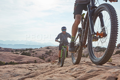 Buy stock photo Cropped shot of two athletic men mountain biking through the wilderness