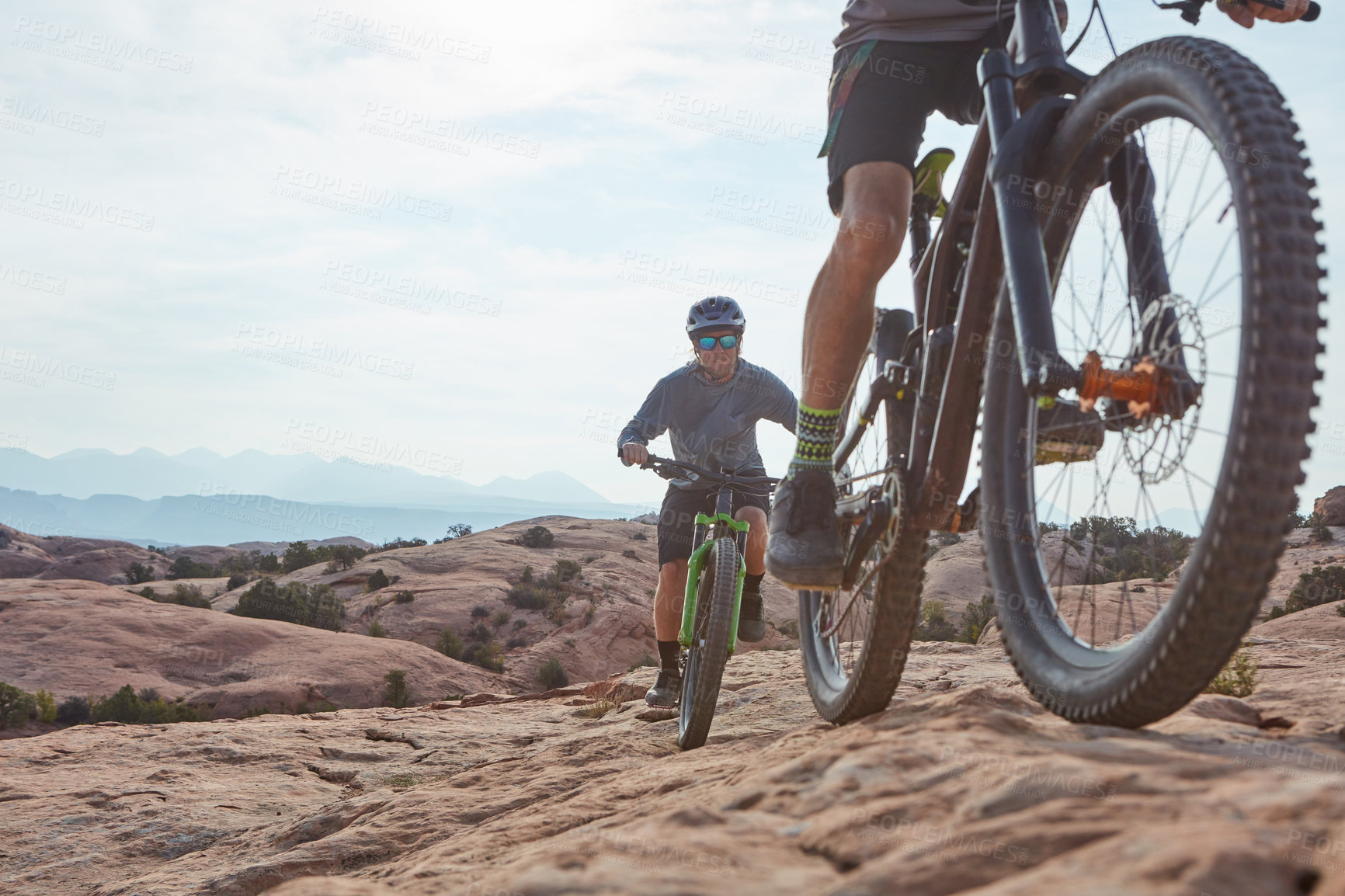 Buy stock photo Cropped shot of two athletic men mountain biking through the wilderness