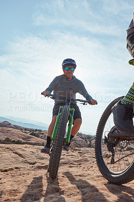 Buy stock photo Cropped shot of two athletic men mountain biking through the wilderness