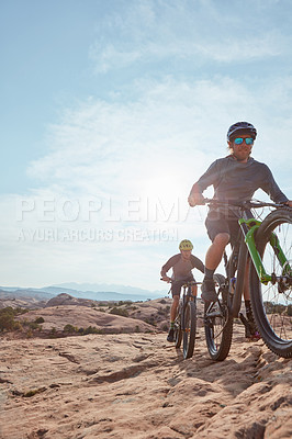 Buy stock photo Cropped shot of two athletic men mountain biking through the wilderness