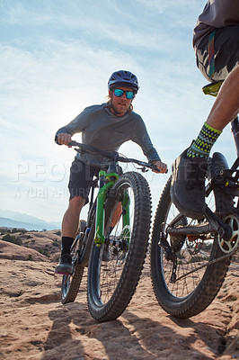 Buy stock photo Cropped shot of two athletic men mountain biking through the wilderness