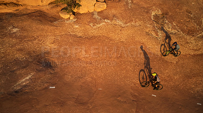 Buy stock photo High angle shot of two young male athletes mountain biking in the wilderness