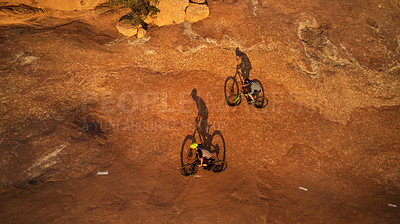 Buy stock photo High angle shot of two young male athletes mountain biking in the wilderness