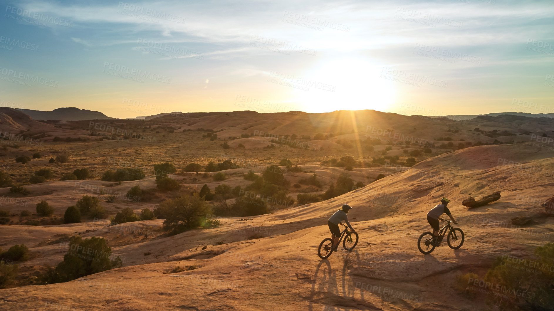 Buy stock photo Full length shot of two young male athletes mountain biking in the wilderness