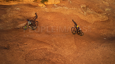 Buy stock photo High angle shot of two young male athletes mountain biking in the wilderness