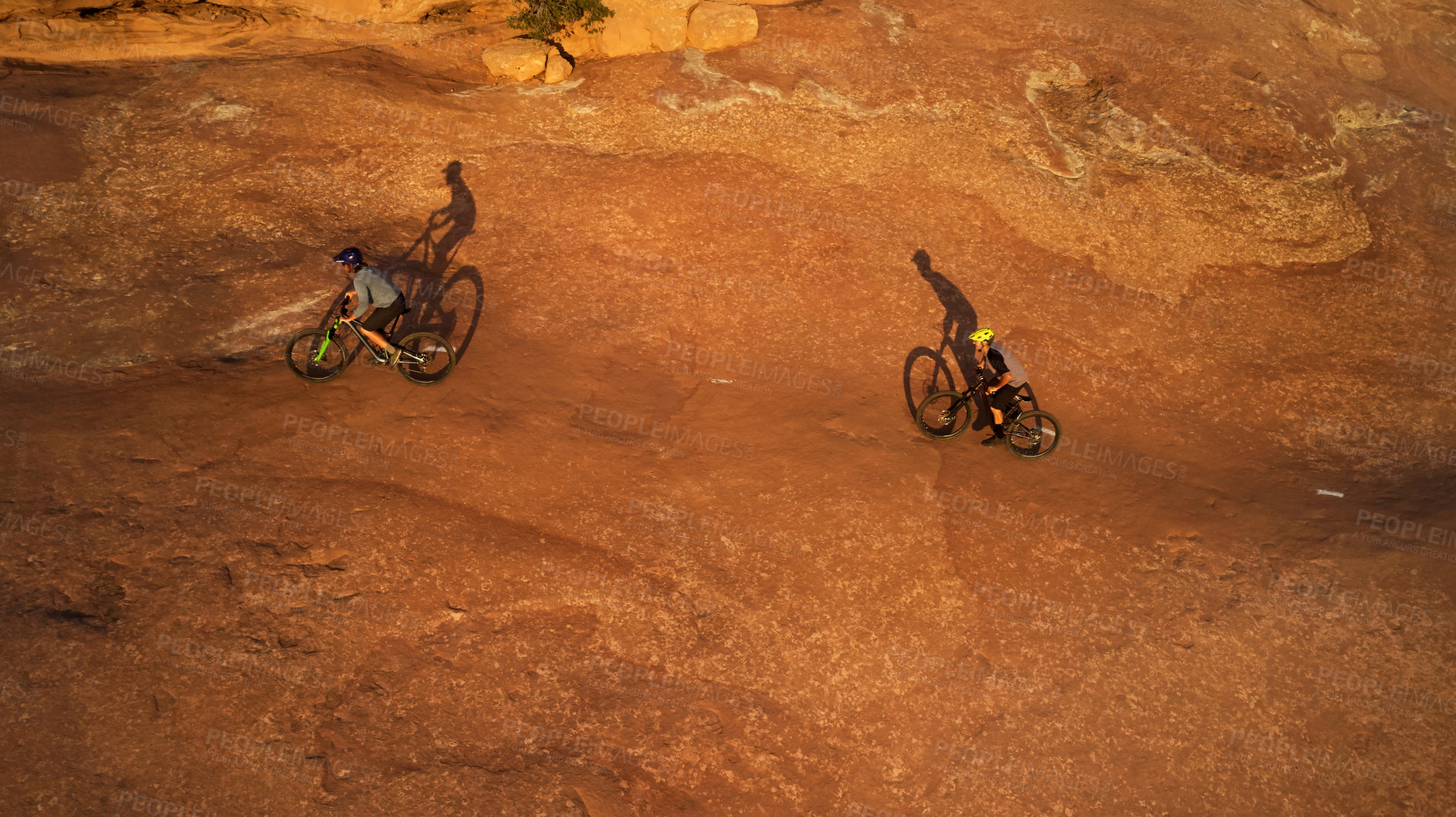 Buy stock photo High angle shot of two young male athletes mountain biking in the wilderness