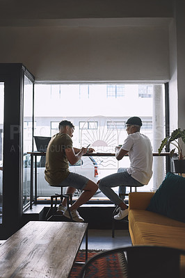 Buy stock photo Shot of two young men having coffee together in a cafe