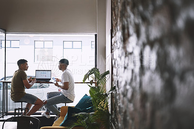 Buy stock photo Shot of two young men doing business while sitting together in a coffee shop