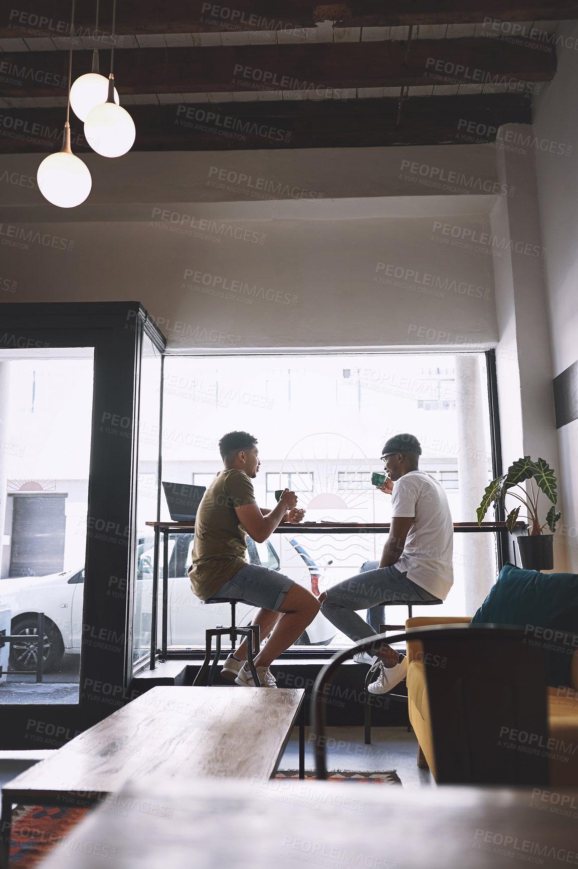 Buy stock photo Shot of two young men having coffee together in a cafe