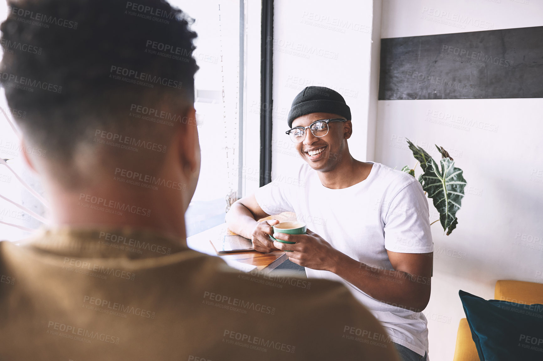 Buy stock photo Shot of two young men having coffee together in a cafe