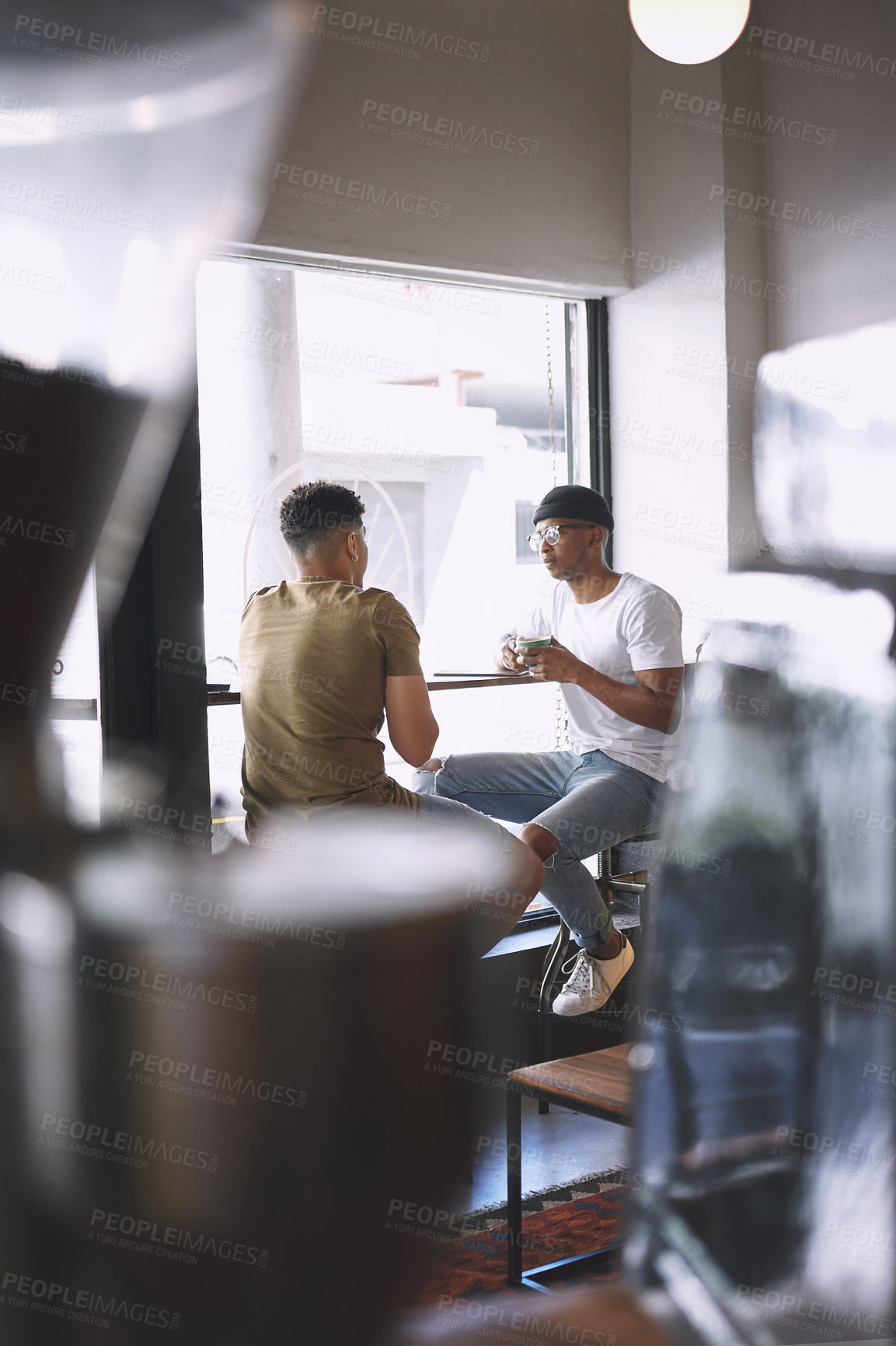 Buy stock photo Shot of two young men talking while having coffee together in a cafe