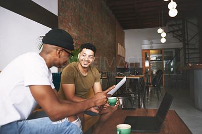 Buy stock photo Shot of two young men discussing business while sitting together in a coffee shop