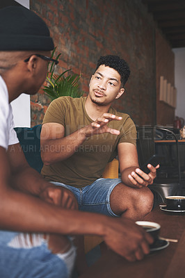 Buy stock photo Shot of two young men having a conversation while sitting together in a coffee shop