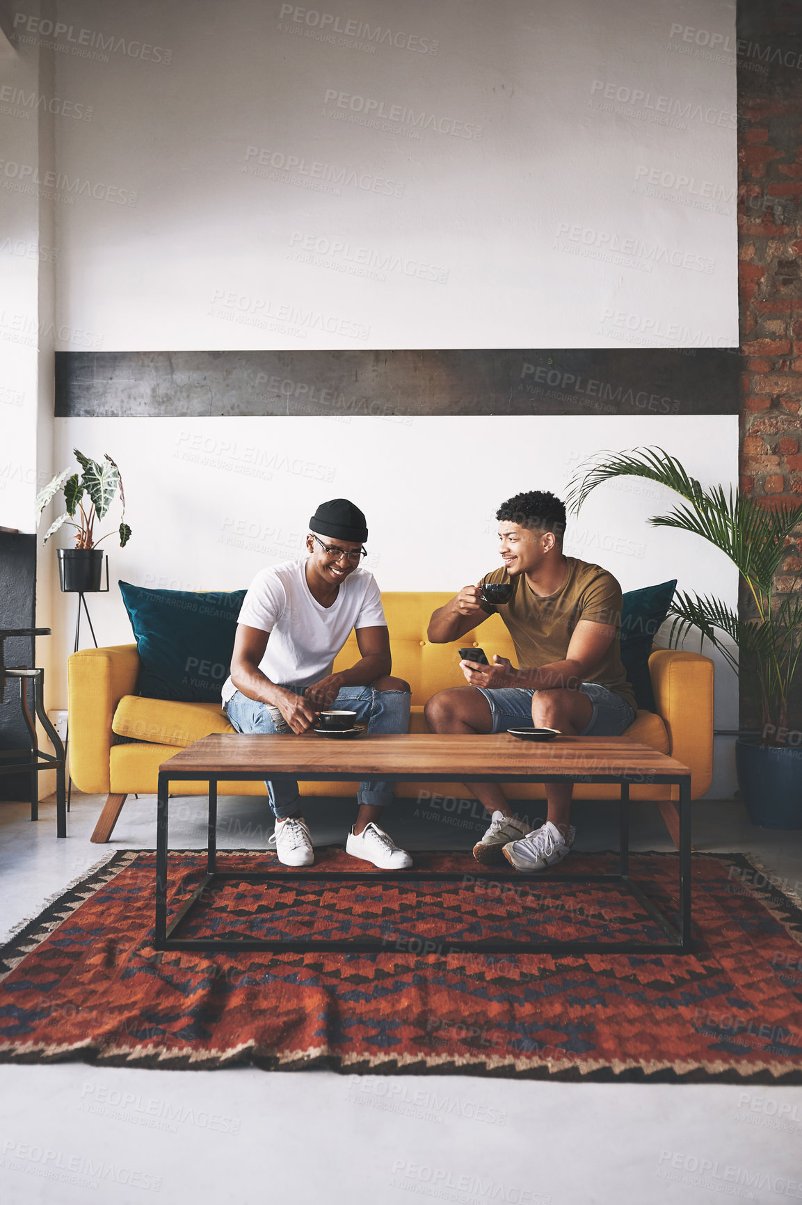 Buy stock photo Shot of two young men sitting together in a coffee shop