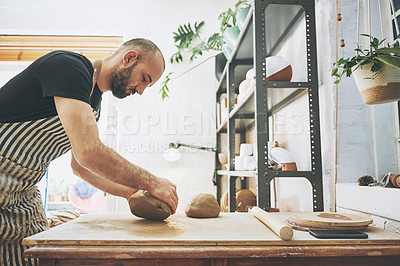 Buy stock photo Shot of a young man kneading clay in a pottery studio
