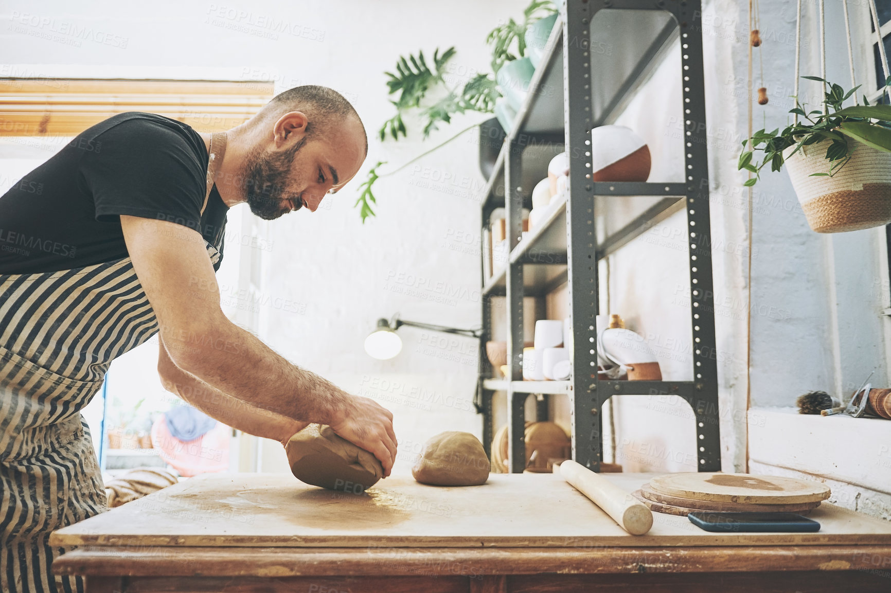 Buy stock photo Shot of a young man kneading clay in a pottery studio