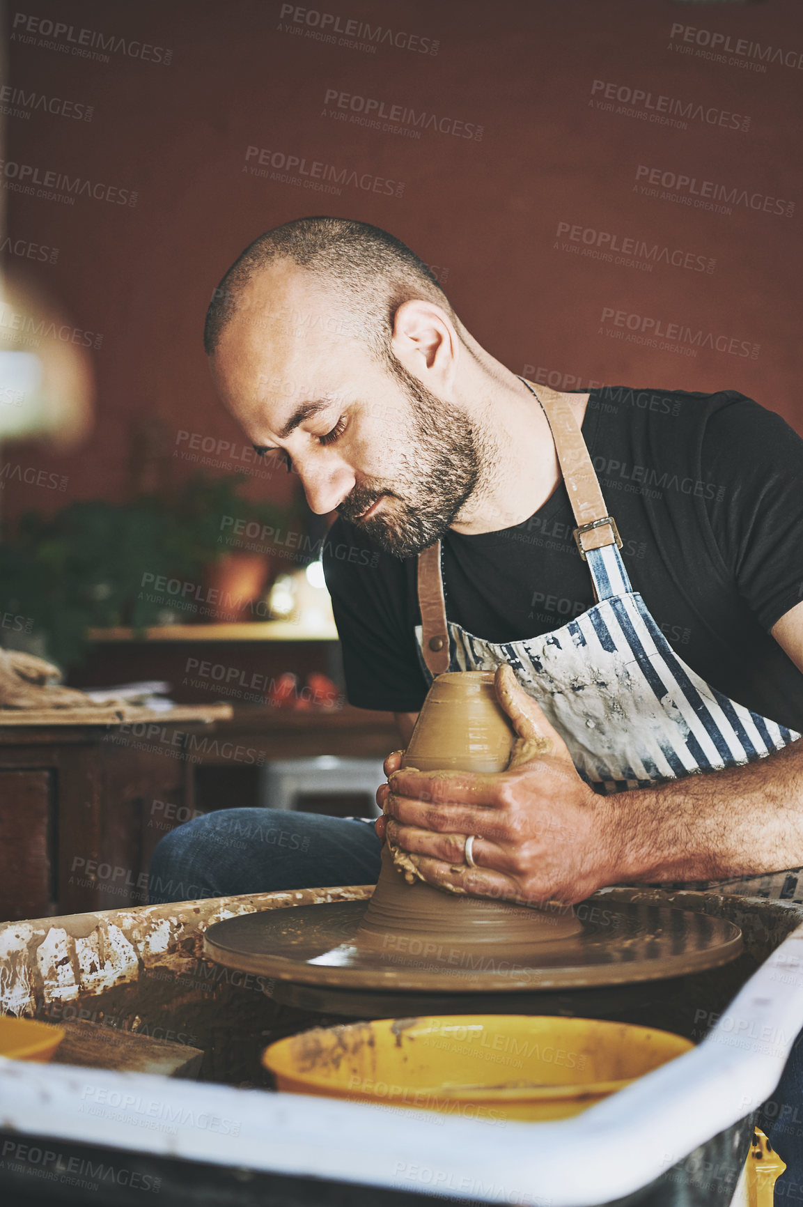 Buy stock photo Shot of a young man working with clay in a pottery studio